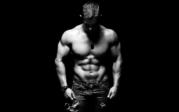 Fitness model displaying a six-pack and muscular arms, in a focused pose against a dark background, suitable for workout motivation. 2000s bodybuilder. https://karanblog.in/