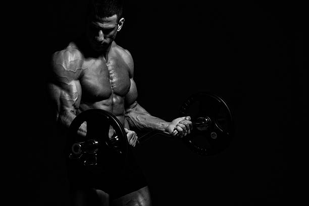 Bodybuilder with strong biceps doing barbell curls, black and white fitness wallpaper for intense workouts. 2000s bodybuilder. https://karanblog.in/